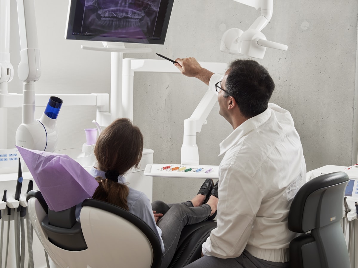 A dentist reviewing a digital X-ray with a patient chairside